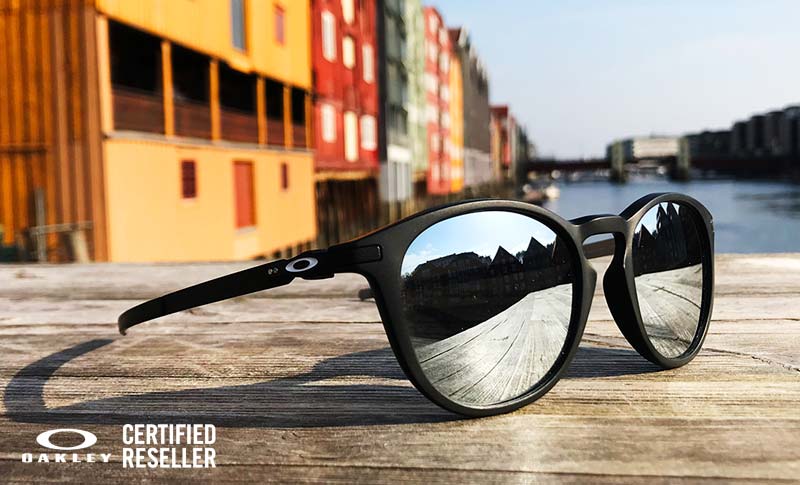 Oakley solbriller på en benk med fine bygg i bakgrunn