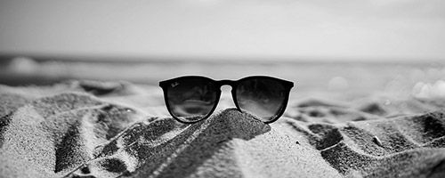 Solbriller i sanden på stranda
